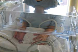 preterm baby in an incuboator mom holding inside