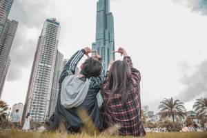young couple sitting n the lawn looking at large buildings