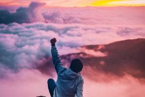 man on mountain top celebrating 