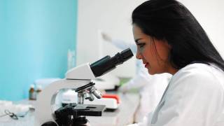 researcher looking thru a microscope
