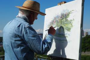 older man painting on a canvas outside
