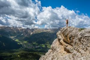 mountain with a person celebrating on the top of it