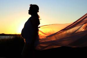 pregnant lady at the beach sun setting wind blowing